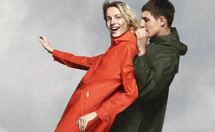 Two models in Hunter raincoats laughing in the rain in the Rain Starts Play campaign
