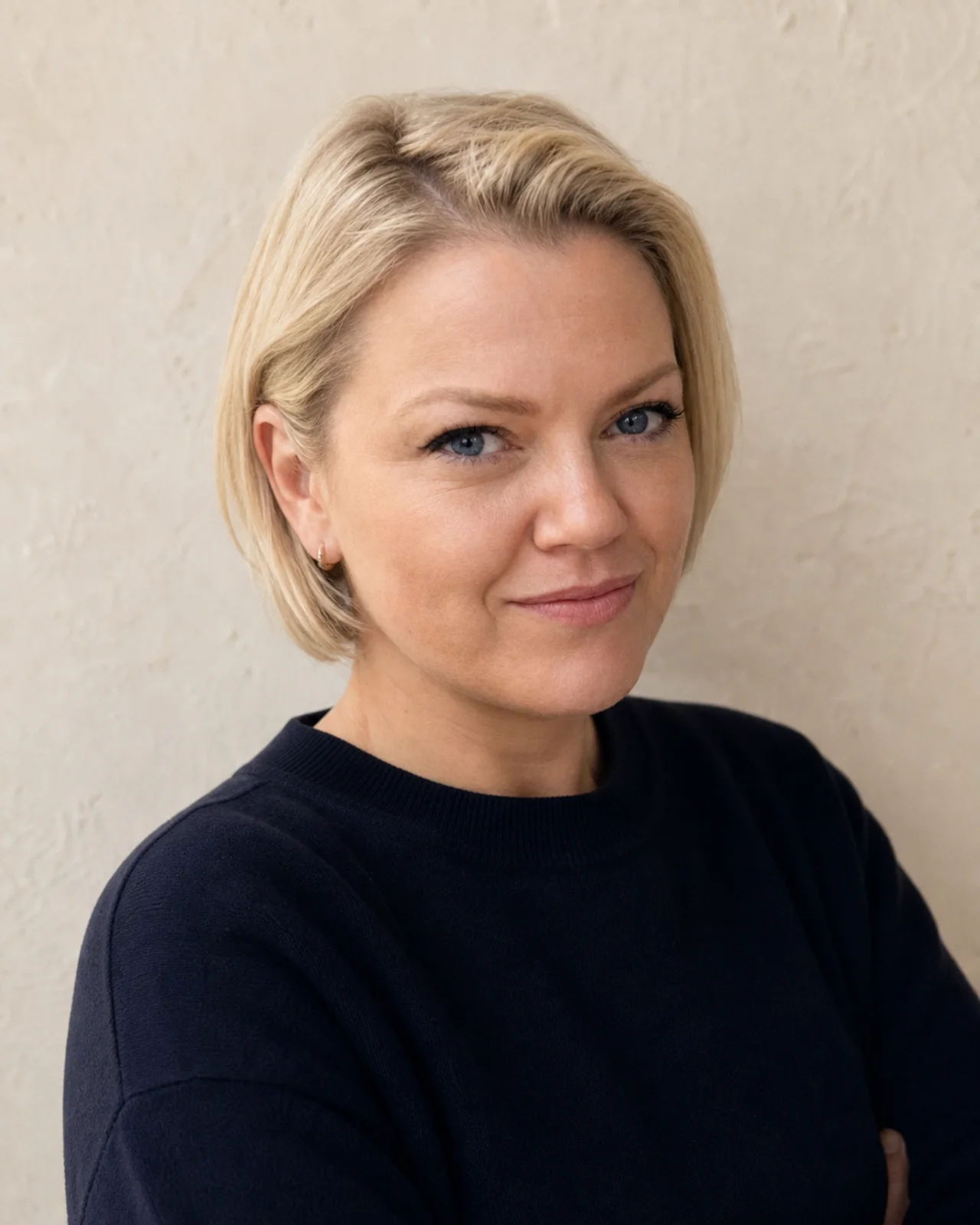 Michelle Sadlier in a dark crew-neck knit against a warm plaster wall