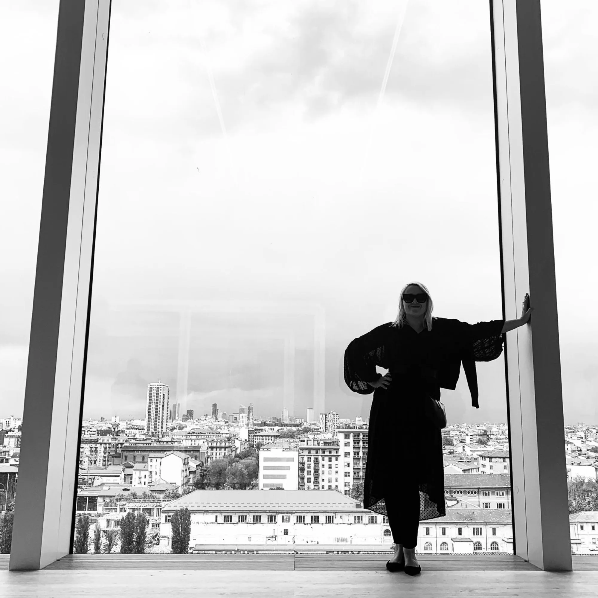 Michelle Sadlier silhouetted in a monumental window high above the Milan skyline